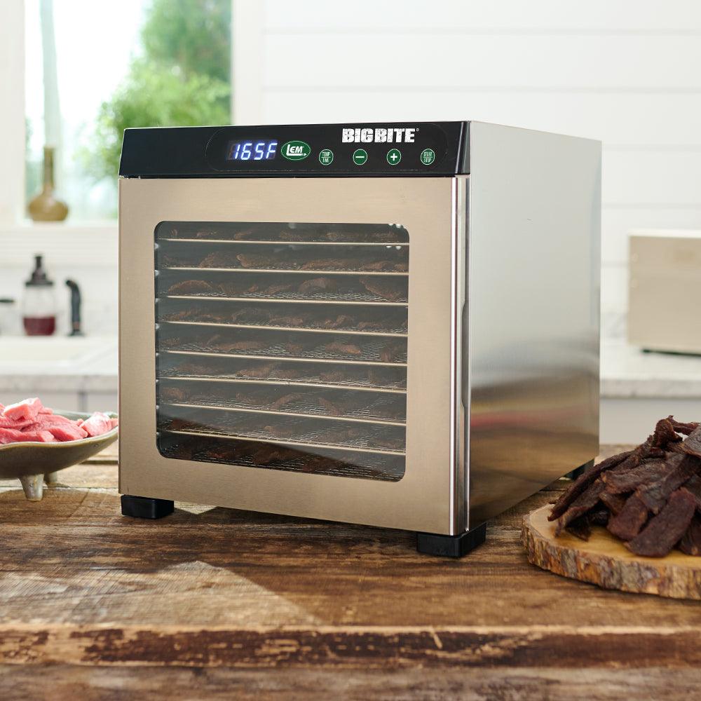 Stainless steel Big Bite 10-tray food dehydrator on wood counter with jerky and meat slices