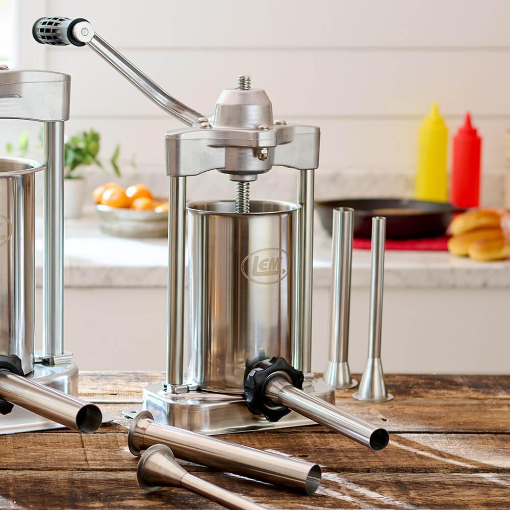 LEM MightyBite 5 lb sausage stuffer with stainless steel tubes on a wooden table.