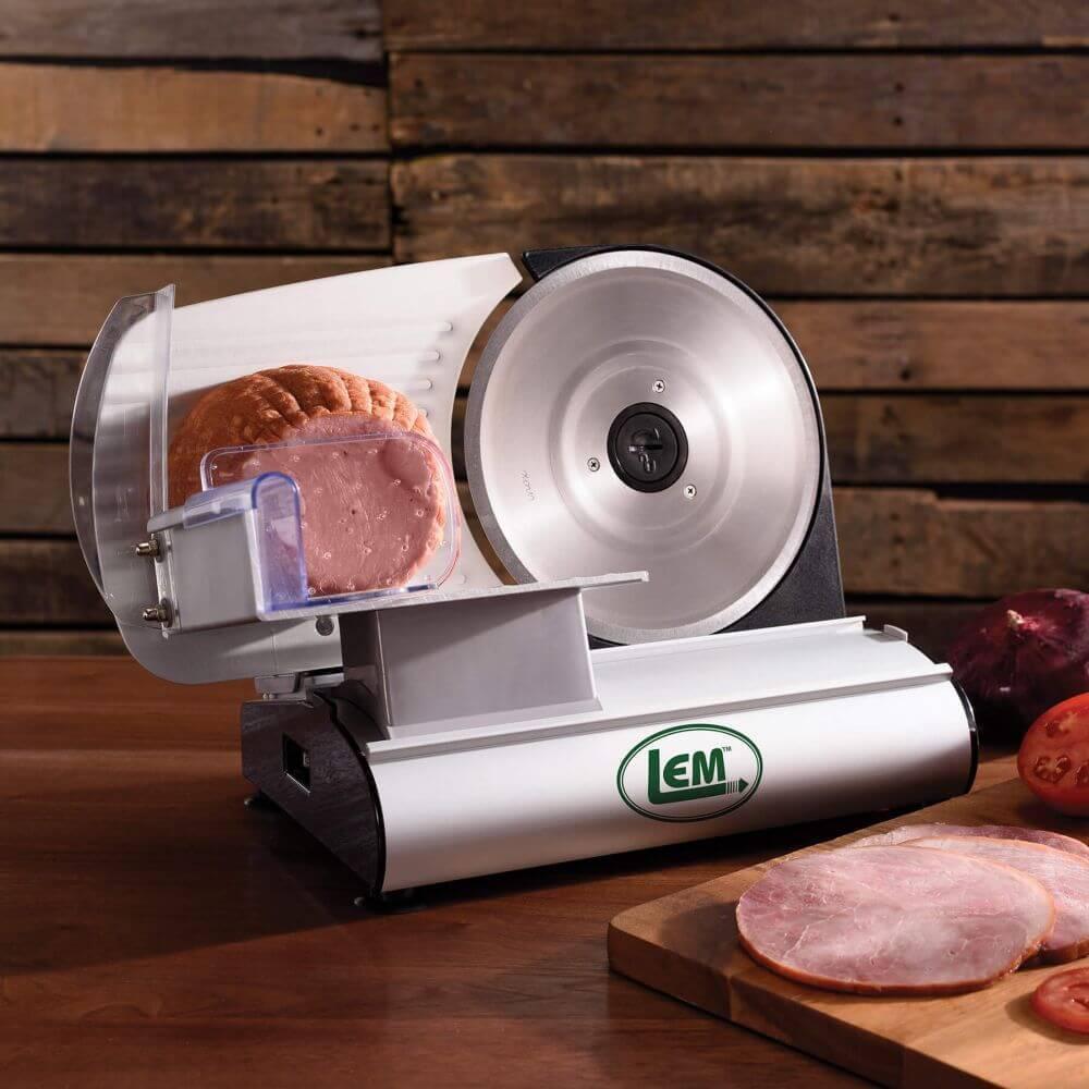 LEM meat slicer on wood table slicing ham with wooden plank background