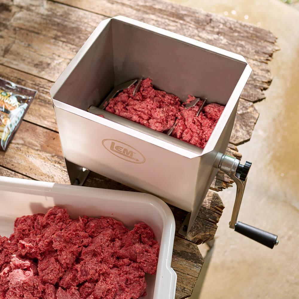 LEM MightyBite manual meat mixer with ground meat on rustic wooden table