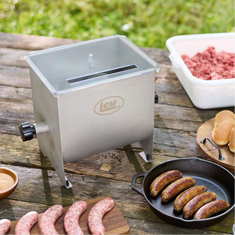 LEM Mighty Bite manual meat mixer on wood table with sausage and ground meat outdoors
