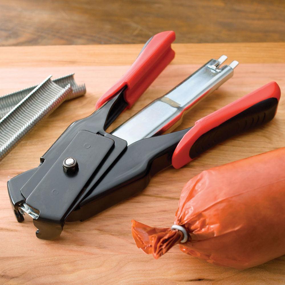 LEM spring-loaded pliers and rings with red handles on wooden surface, sausage casing nearby