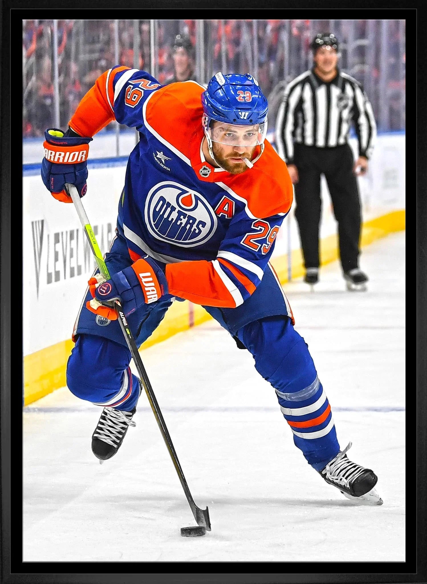 Edmonton Oilers hockey player skating on ice in game action, wearing orange and blue uniform