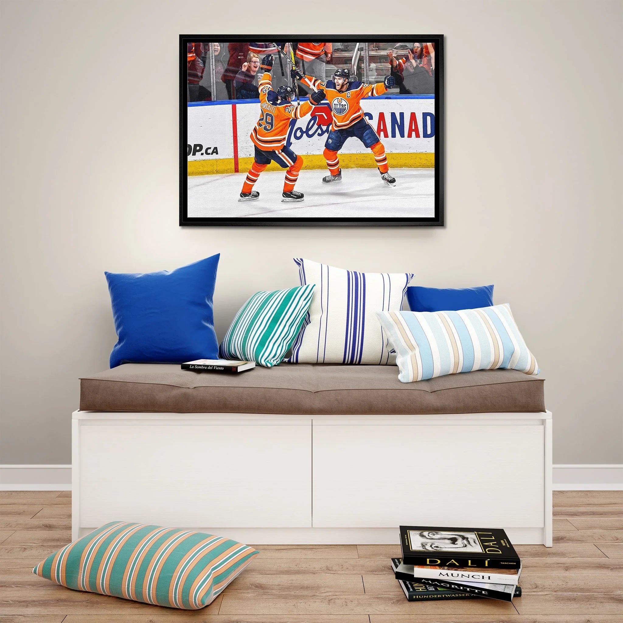 Framed Edmonton Oilers hockey photo above modern bench with striped pillows and books