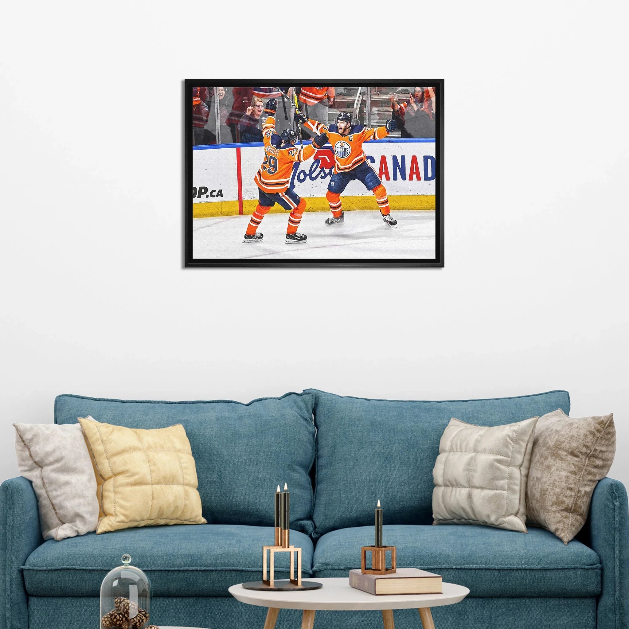 Framed hockey wall art of Edmonton Oilers players celebrating, displayed above blue sofa