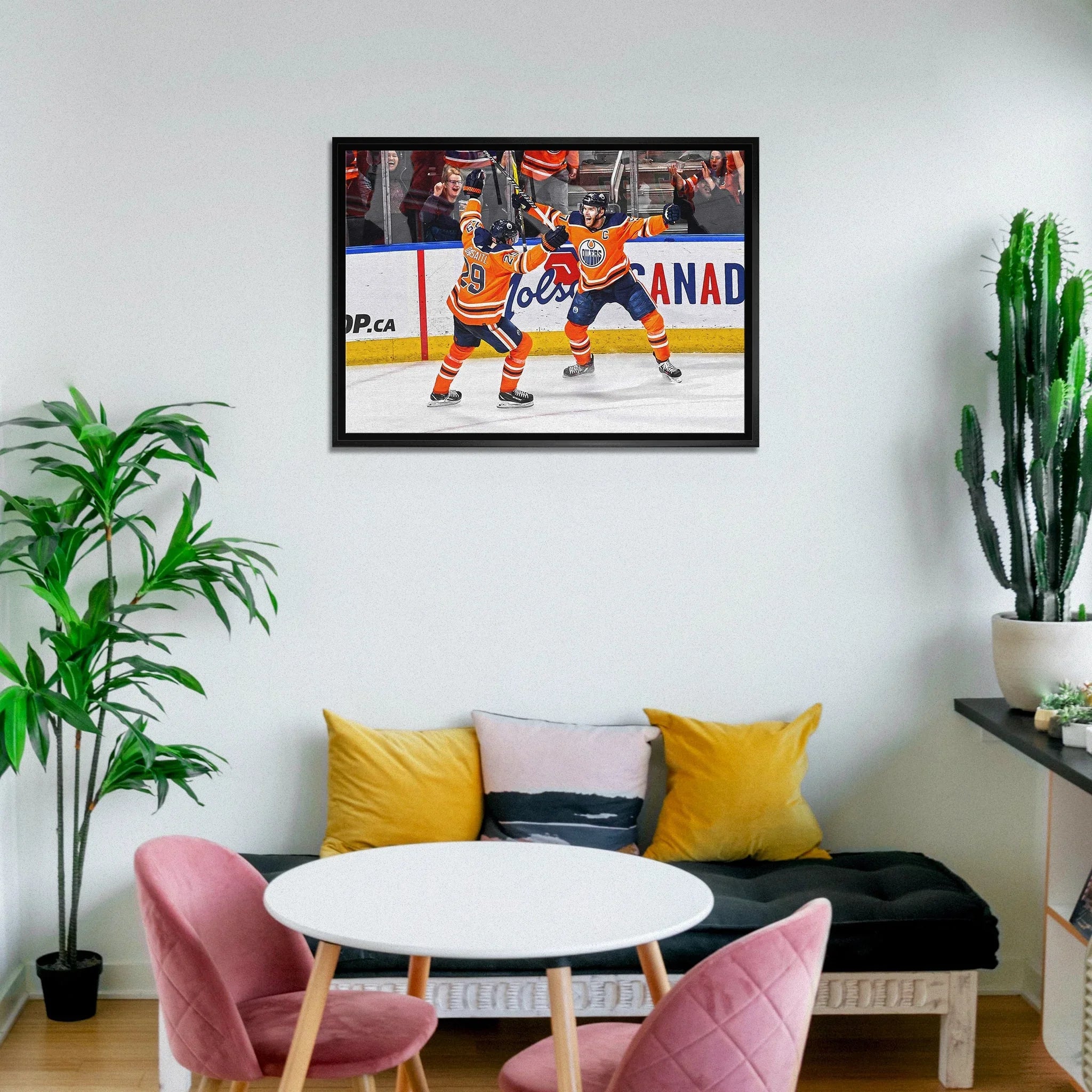Modern living room with framed hockey celebration photo, plants, and pastel chairs