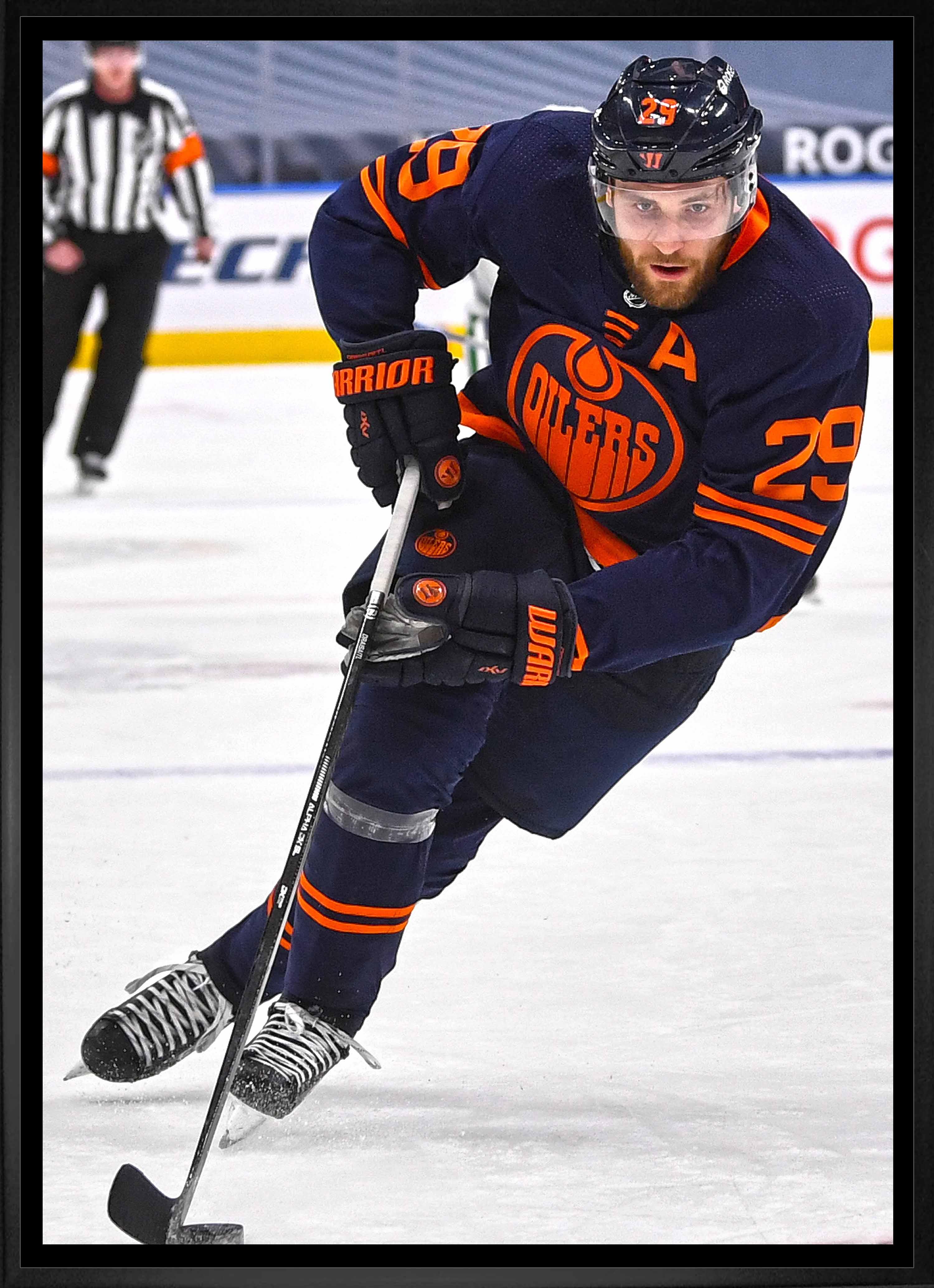 Edmonton Oilers hockey player in navy uniform skating with puck on ice