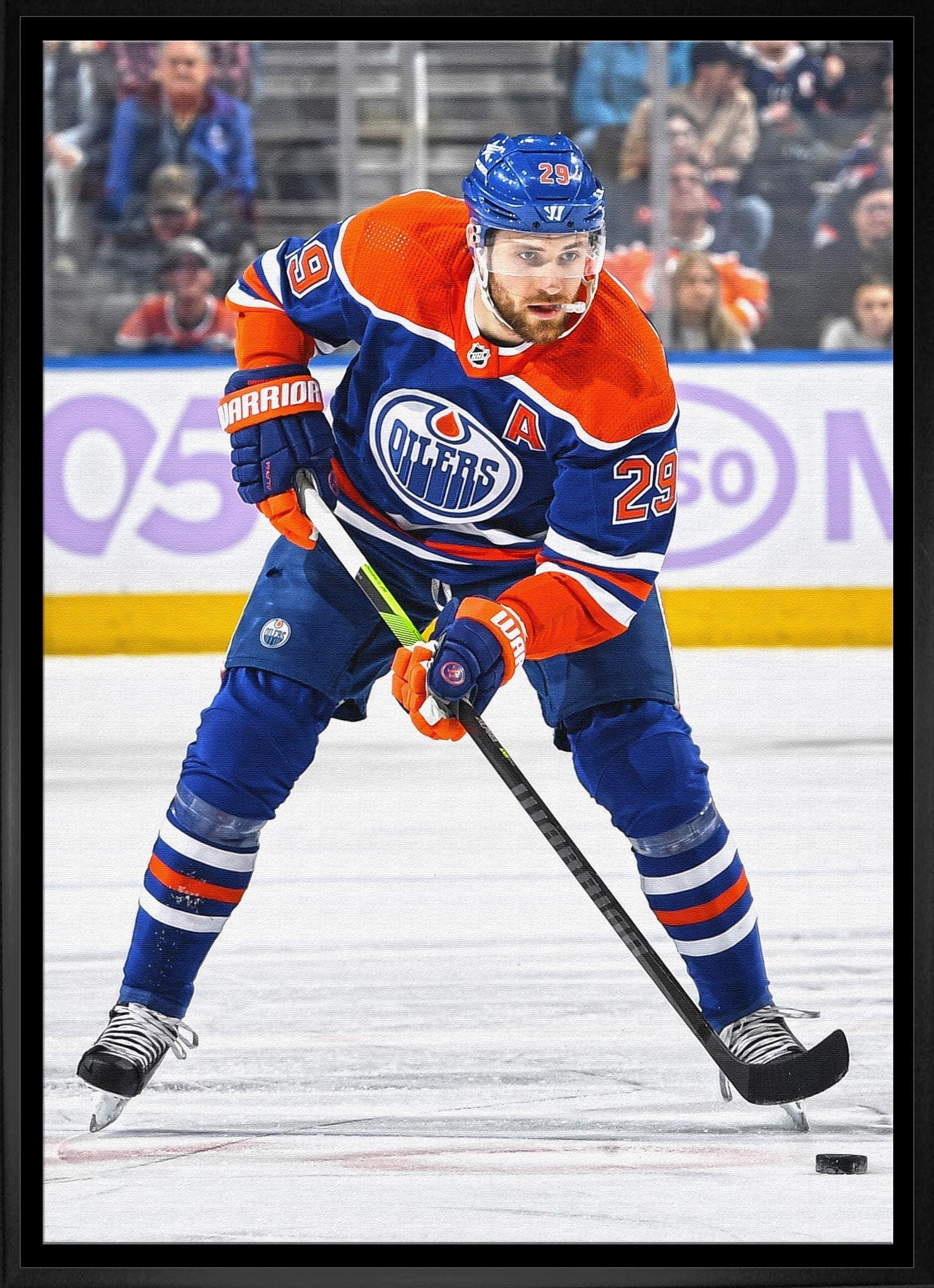 Edmonton Oilers hockey player in blue and orange jersey skating on ice with puck