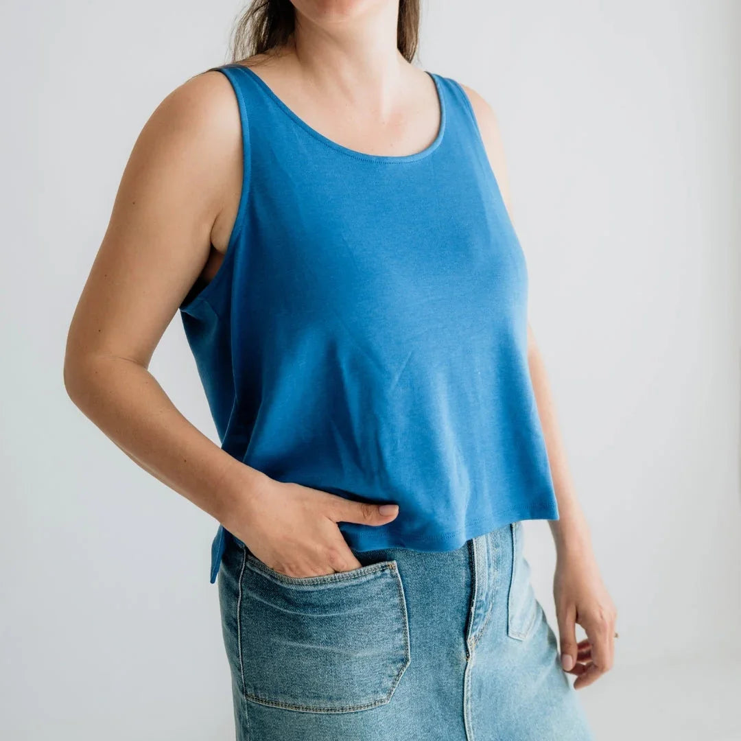 Woman wearing a blue tank top and denim skirt in a minimalist studio setting