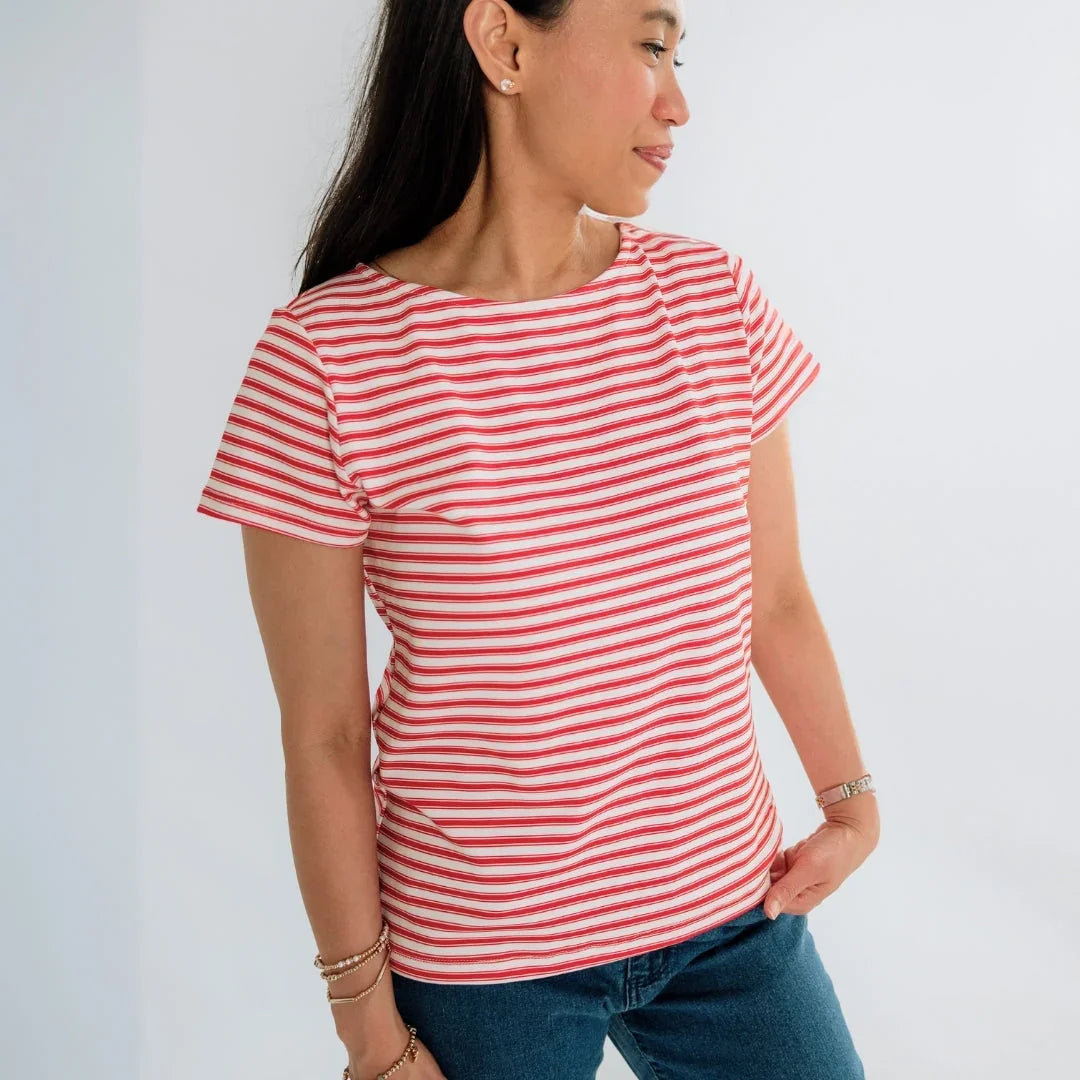 Woman in red and white striped t-shirt and blue jeans posing against white background