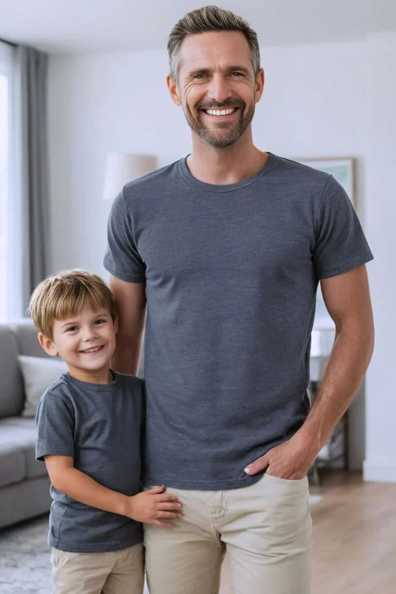 Man and boy wearing matching grey bamboo t-shirts and beige pants, smiling indoors