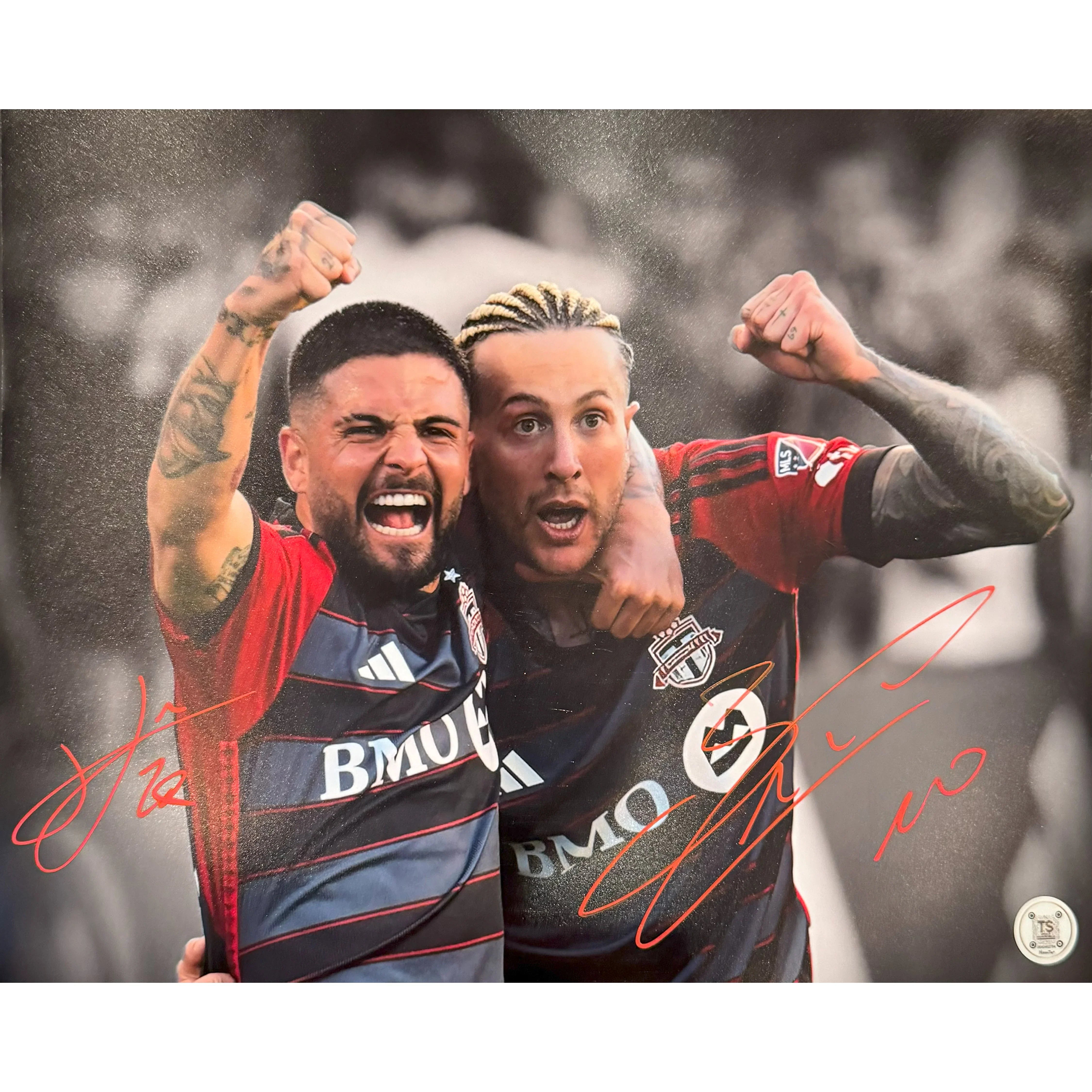 Two Toronto FC soccer players celebrating with arms raised, wearing red and black jerseys