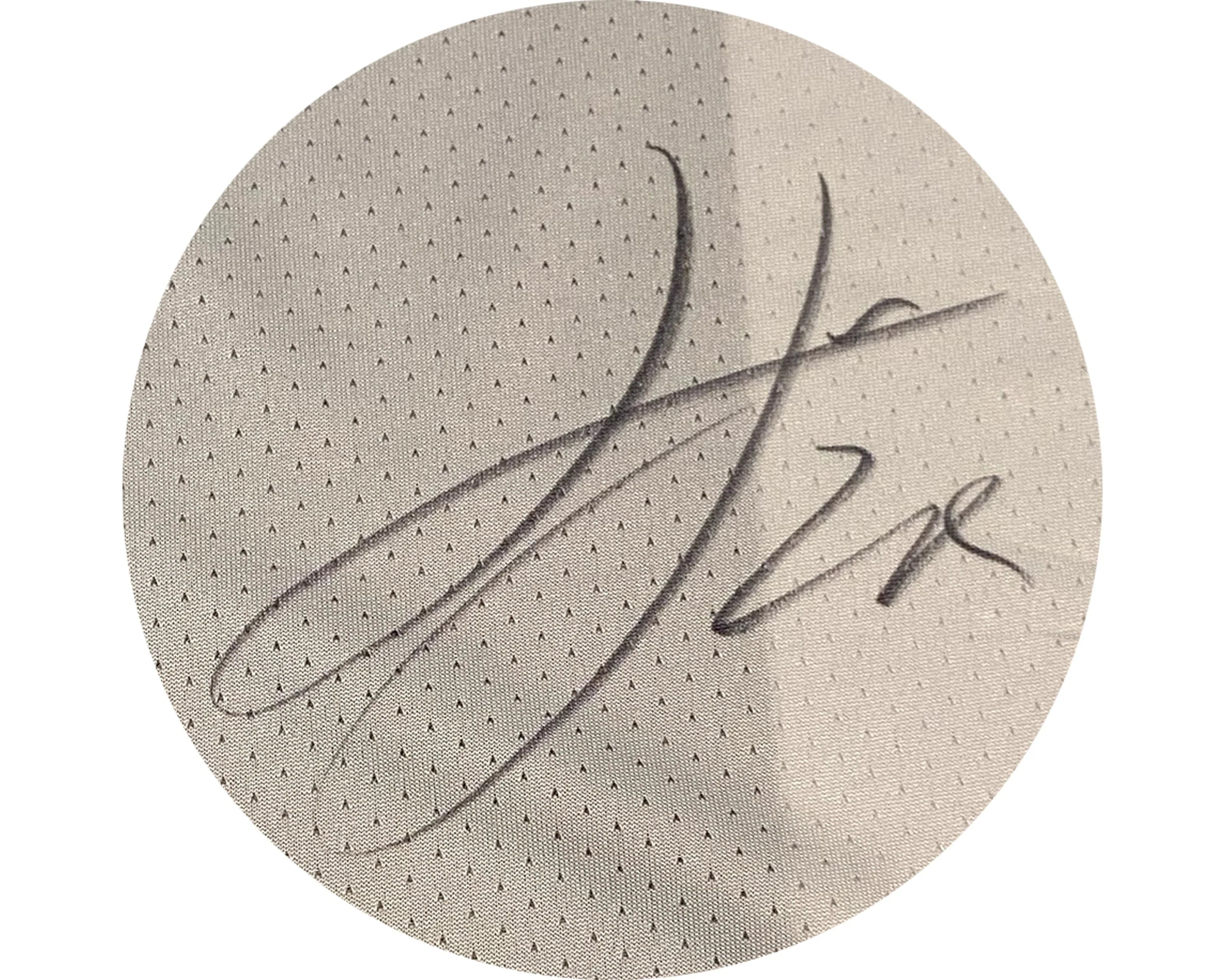Signature on light grey perforated fabric, close-up, autographed sports apparel texture