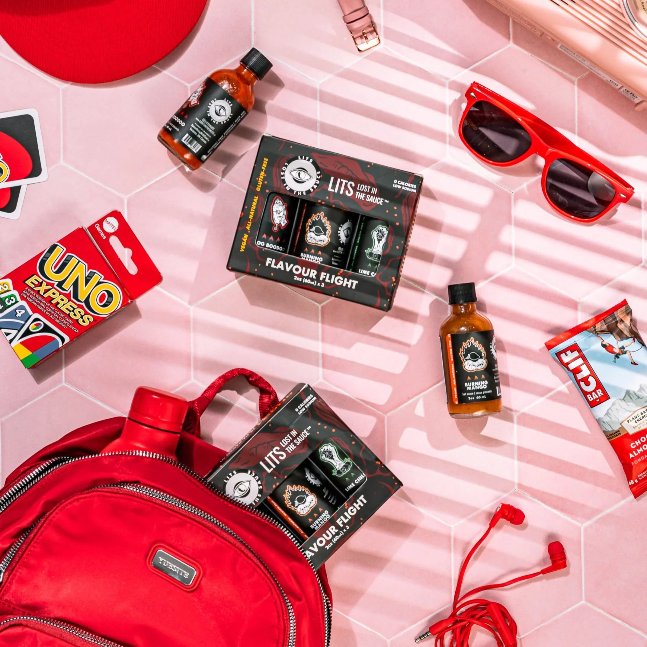 Lost in the Sauce Flavour Flight hot sauce set on pink tile with travel and snack items