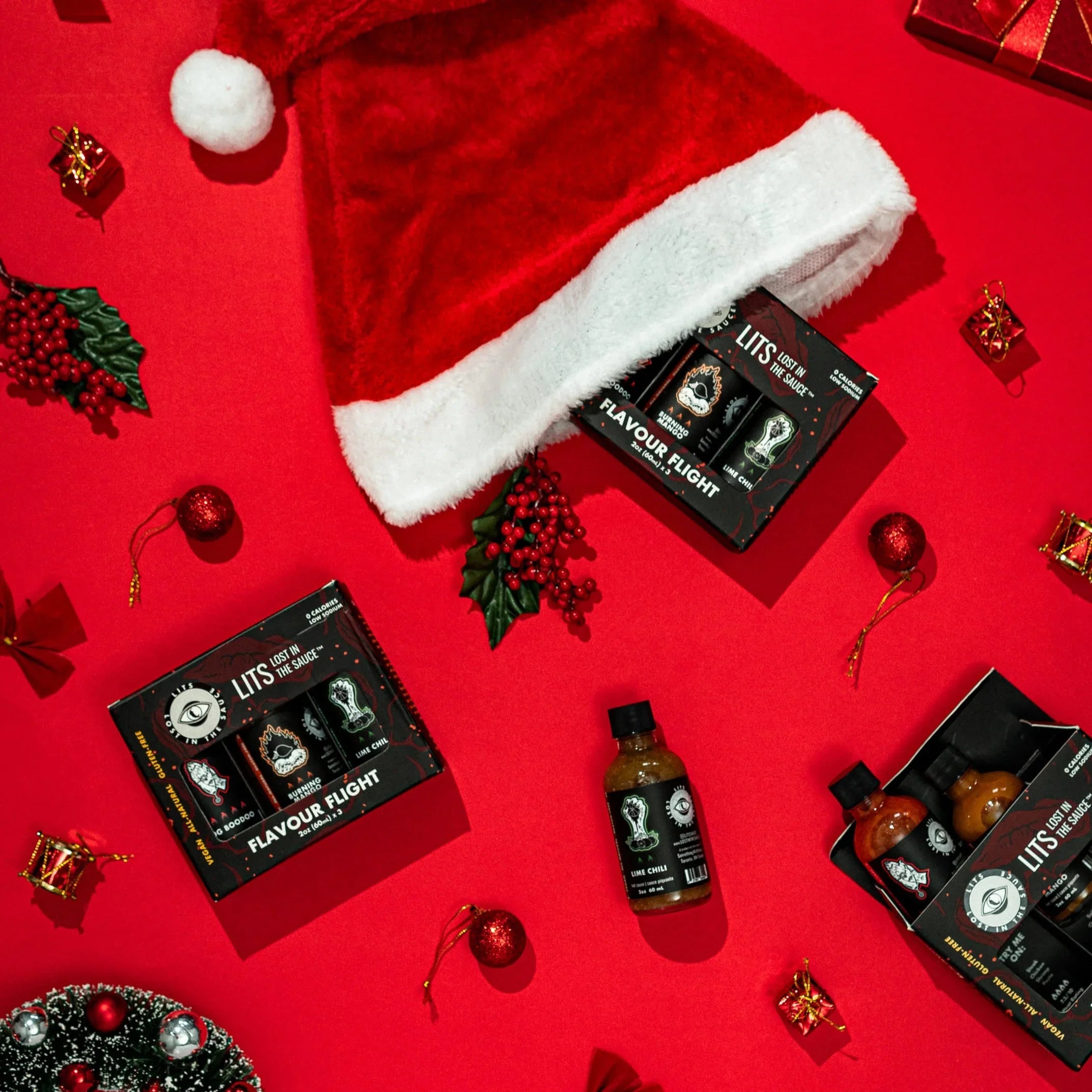 Holiday gift set with LITS Flavour Flight hot sauce trio, Santa hat, and festive red decor