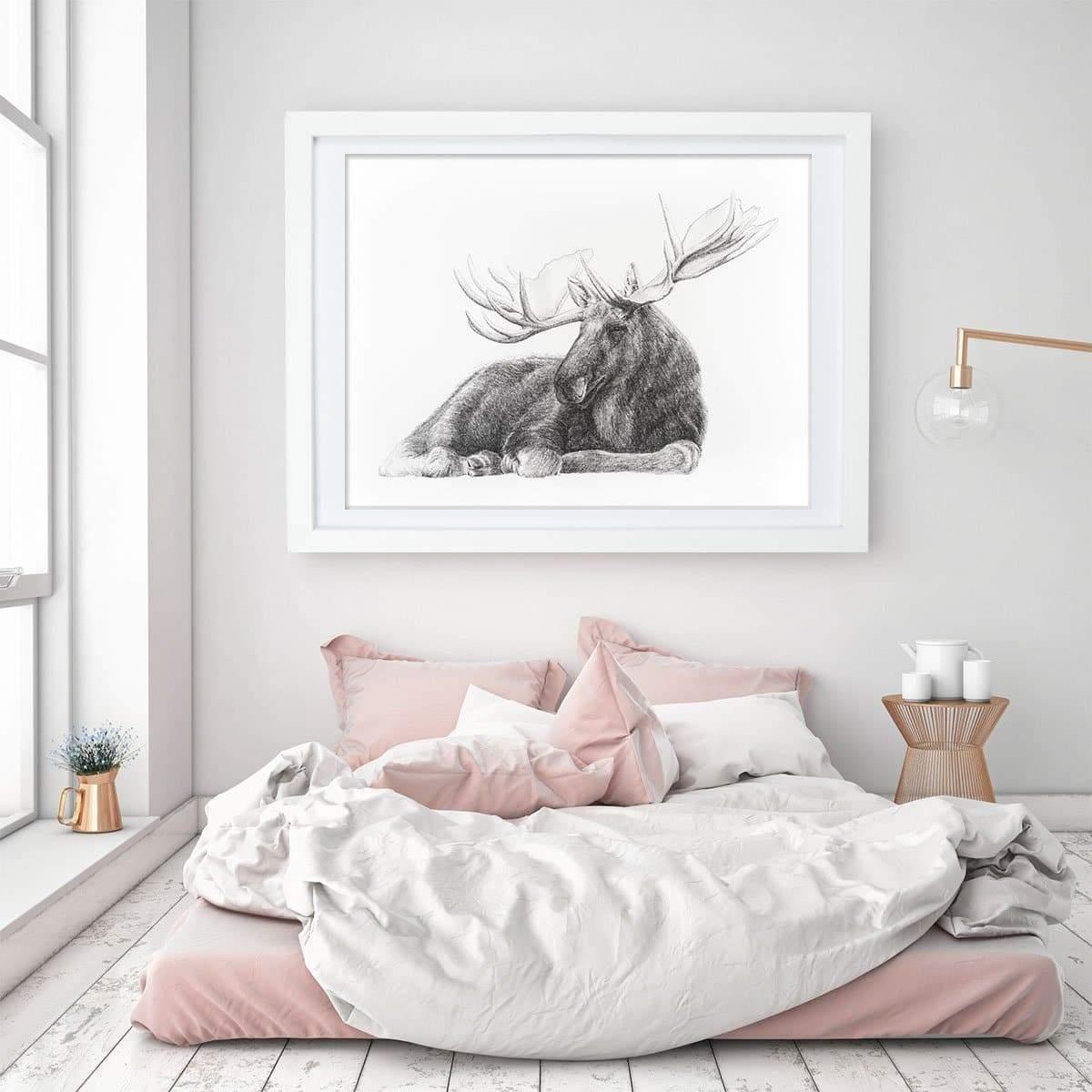 Minimalist bedroom with pink bedding, framed moose wall art, and soft natural light