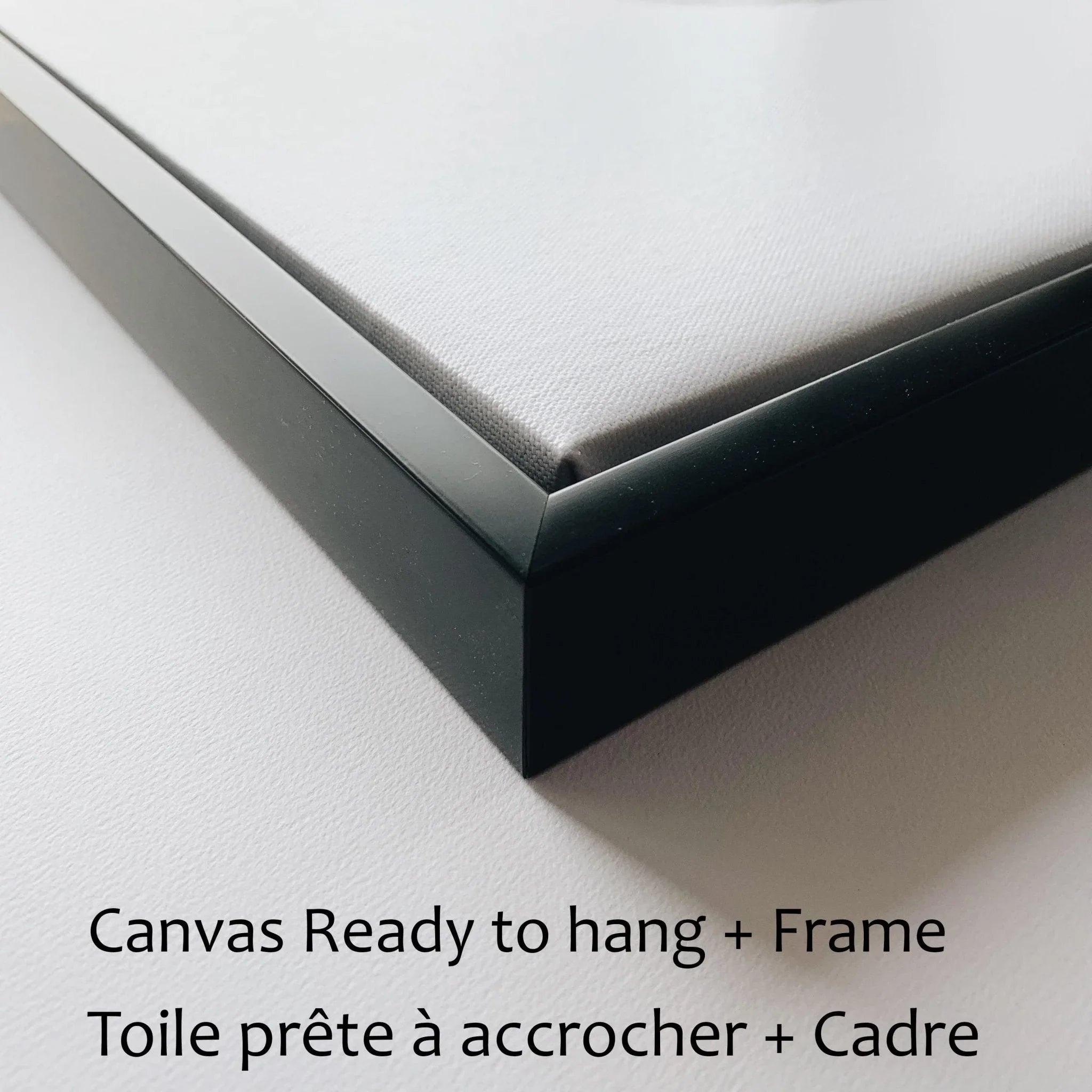 Close-up of black framed canvas, ready to hang, on white background with bilingual text.