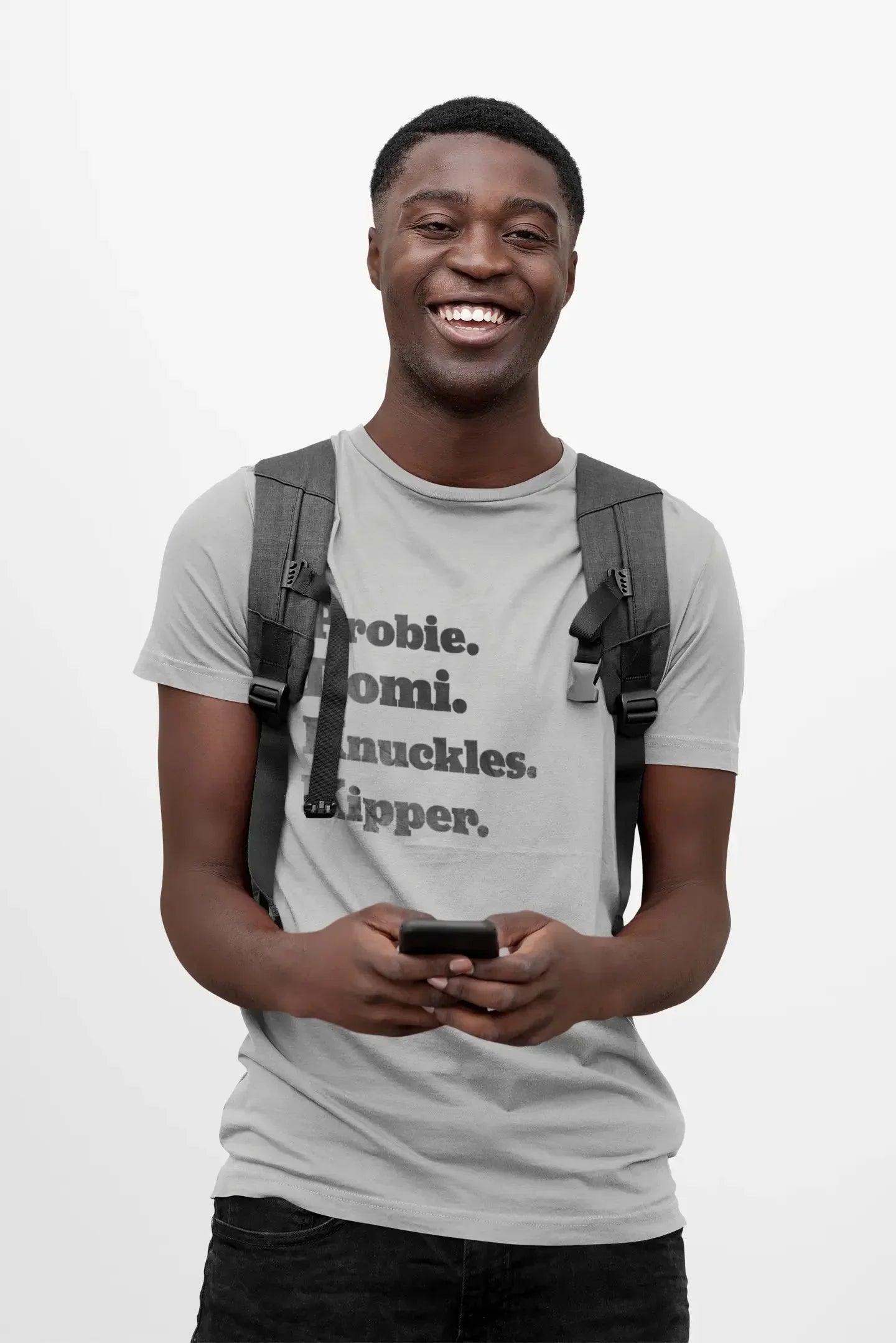 Smiling man in gray t-shirt with bold text, wearing backpack and holding smartphone on white background