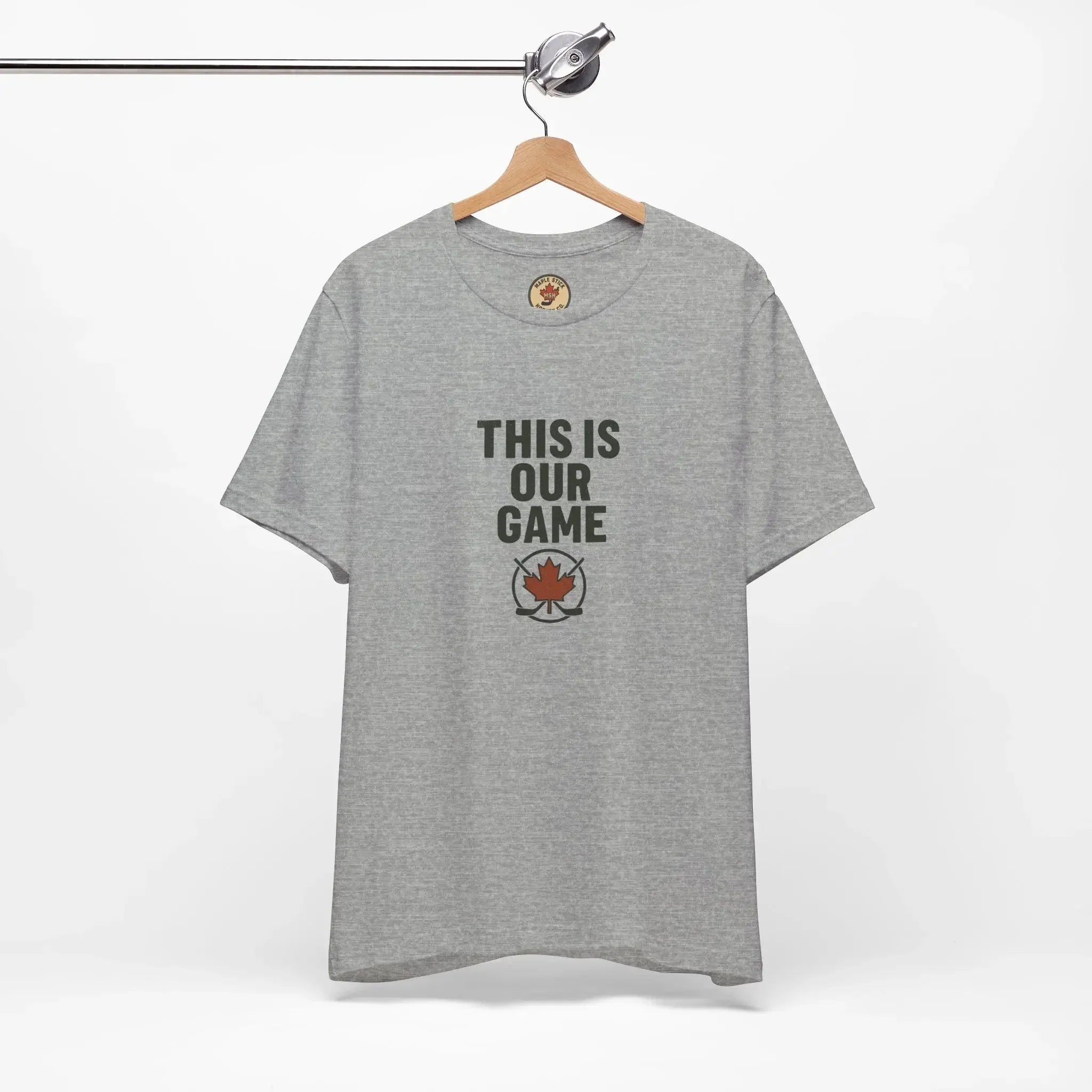 Grey t-shirt on hanger with 'THIS IS OUR GAME' text and maple leaf emblem