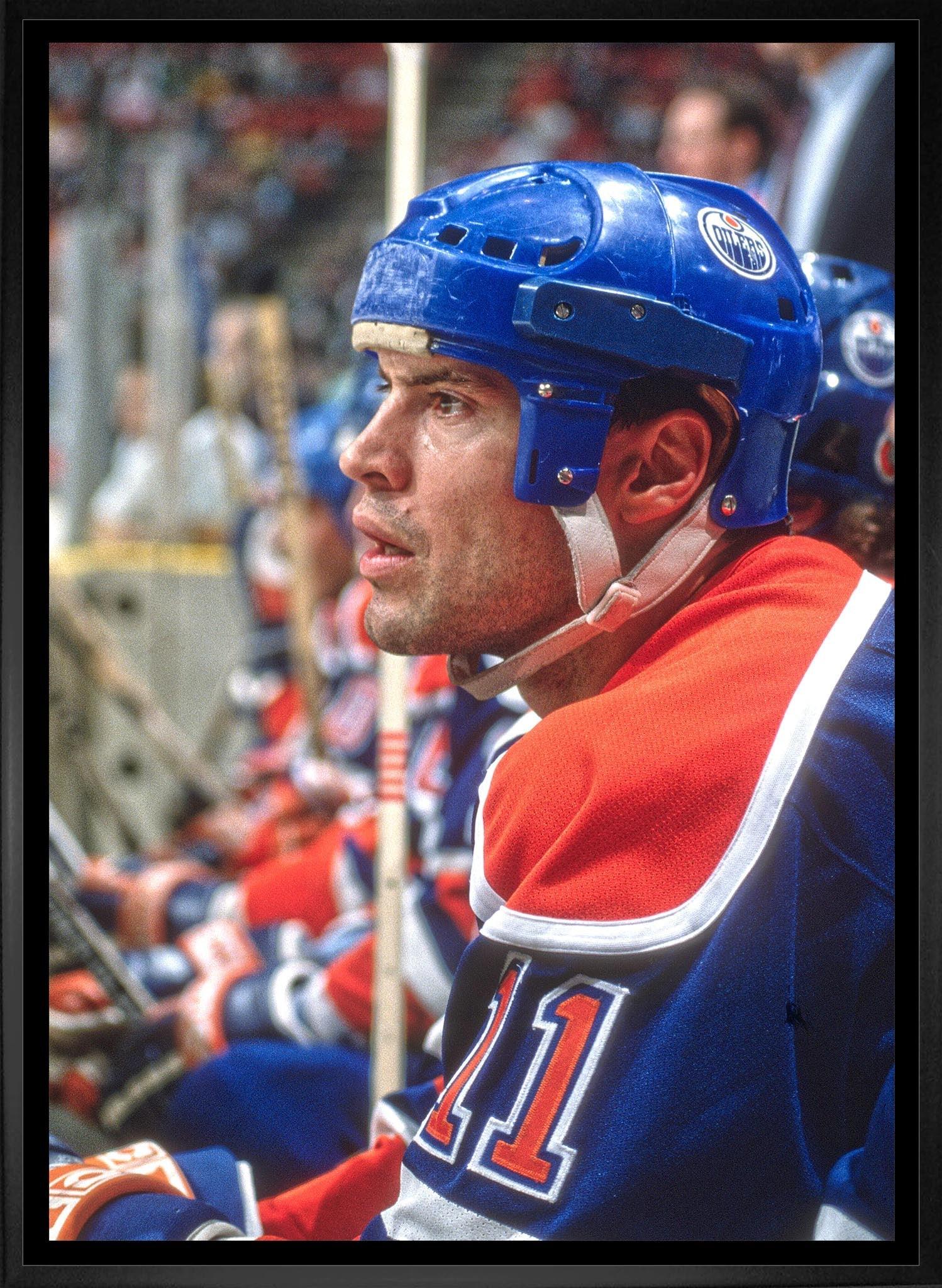 Edmonton Oilers hockey player in blue helmet and jersey number 11 sitting on the bench