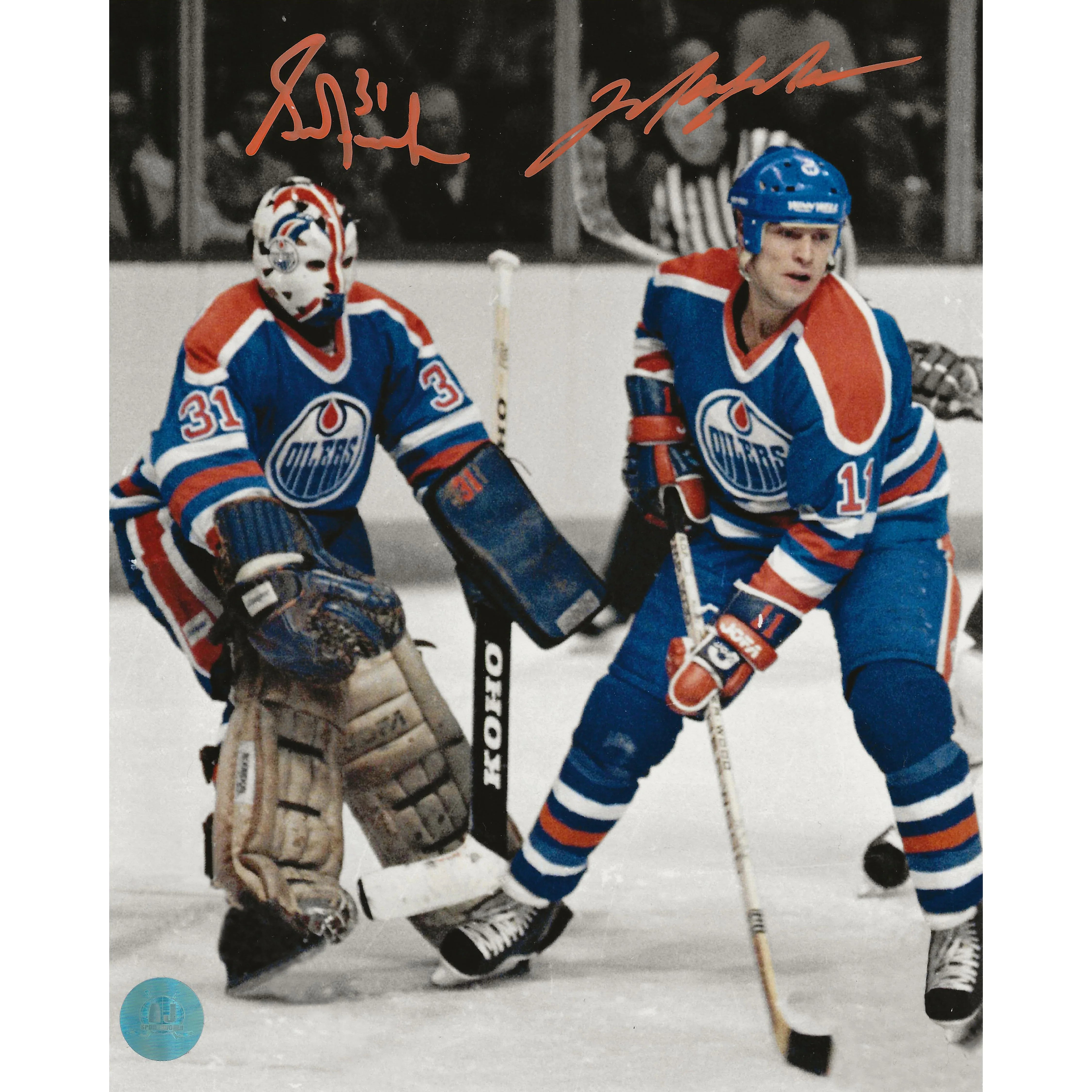 Two Edmonton Oilers hockey players in blue uniforms on ice, with goalie equipment and signed autographs.