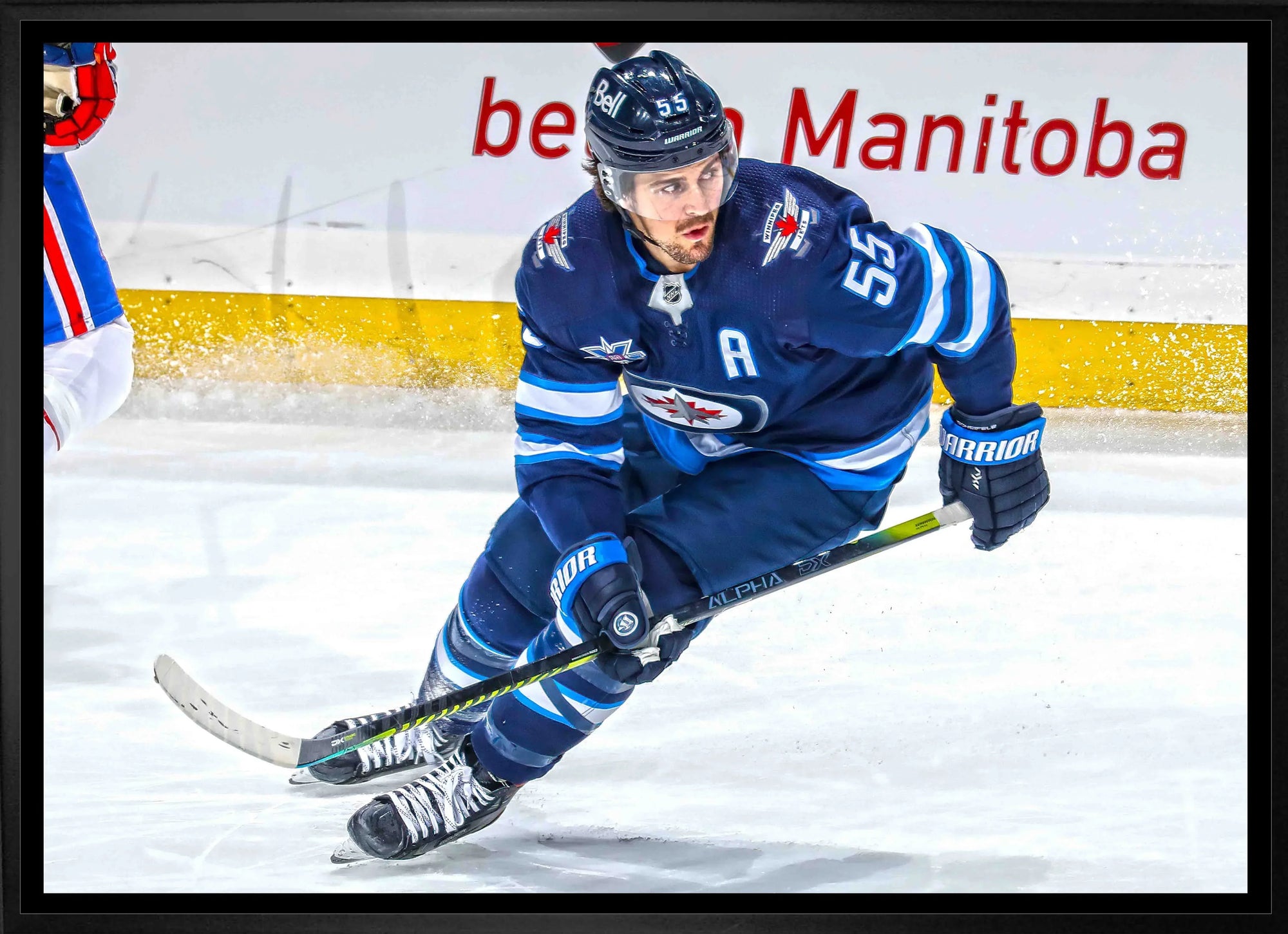 Winnipeg Jets hockey player in blue uniform skating on ice during a game
