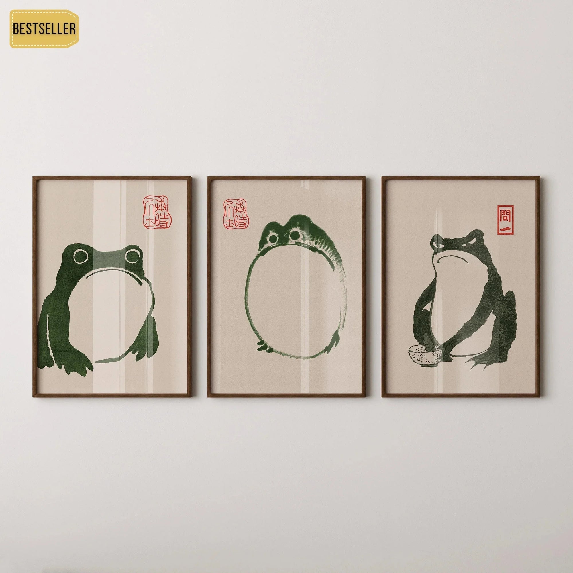 Trio of framed vintage Japanese woodblock prints featuring green frogs on a white wall