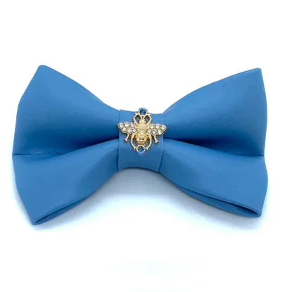 Blue bow tie with gold bee brooch and rhinestones on white background