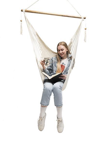 Woman sitting in a natural Mayan hammock chair, reading, on a white background