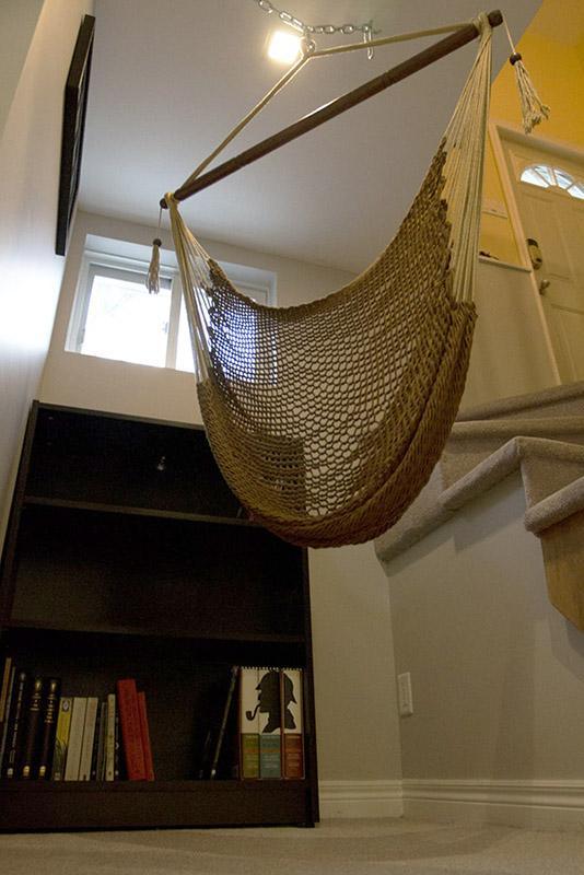 Mayan hanging chair indoors near stairs and bookshelf in modern home setting