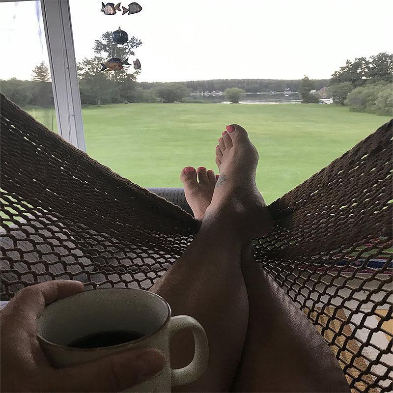 Relaxing in a Mayan hanging chair hammock with coffee, overlooking a green lawn and trees