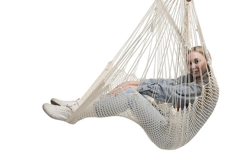Woman relaxing in a natural Mayan hammock chair against a white background
