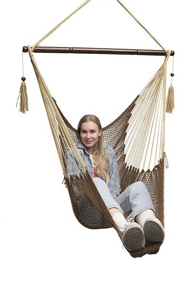 Woman sitting in a brown Mayan hammock chair with wooden spreader bar on white background