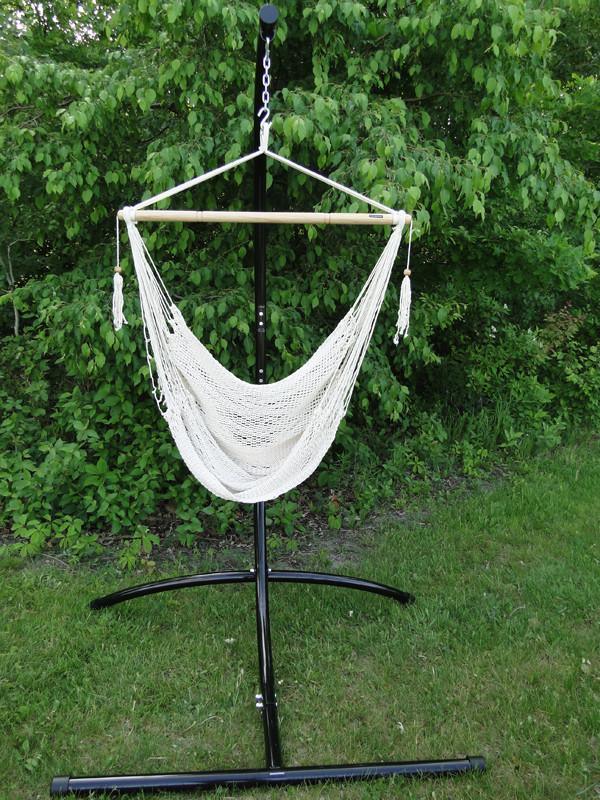 Mayan white hammock chair with metal stand outdoors on green grass and leafy background