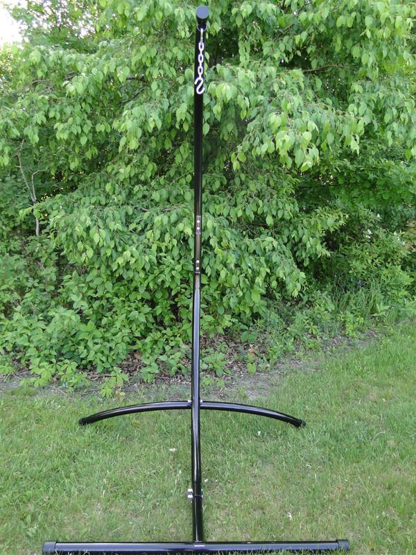 Black steel hammock chair stand on grass with green leafy background outdoors