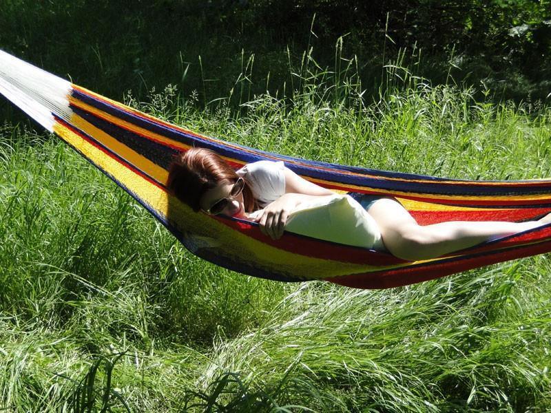 Woman relaxing in a colorful Mayan hammock double size outdoors on green grass
