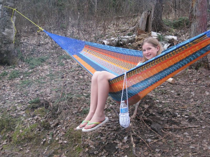 Girl relaxing in a large colorful Mayan hammock outdoors in the woods
