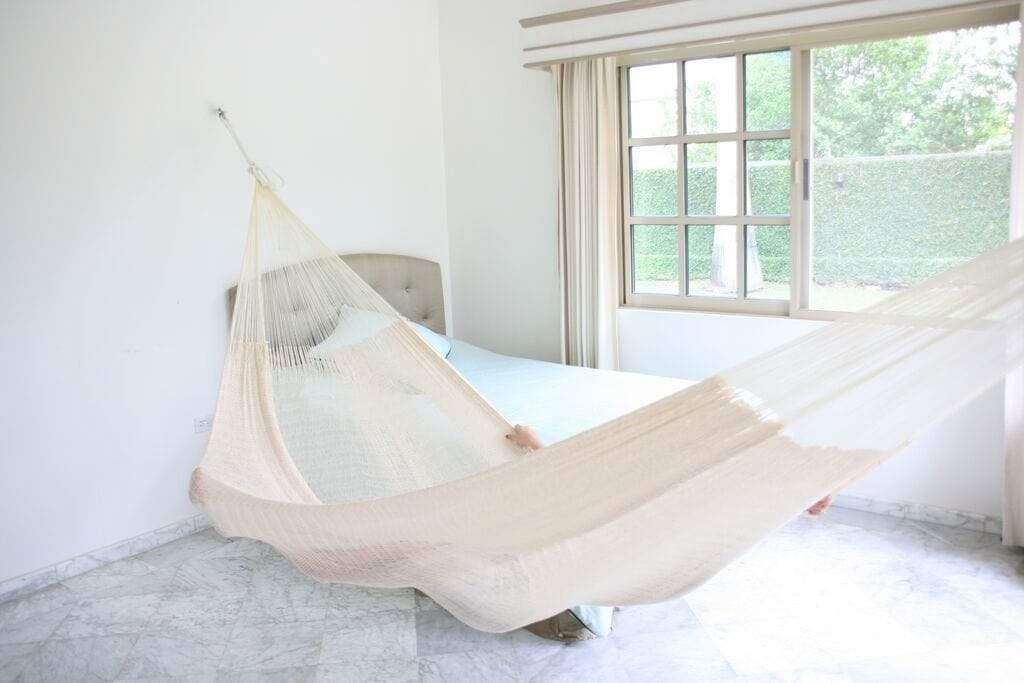 Natural Mayan double hammock in a bright bedroom with marble floor and large window