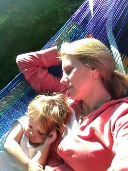 Woman and child relaxing on a colorful Mayan hammock outdoors in sunlight