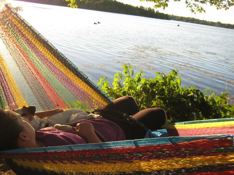 Person relaxing in colorful Mayan hammock beside lake, outdoor hammock scene