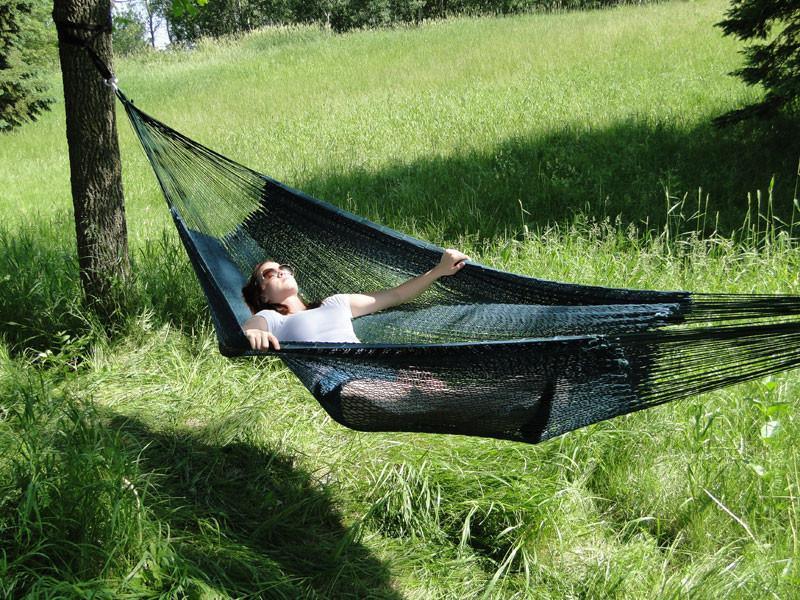 Man relaxing in an XL thick cord Mayan hammock outdoors on green grass