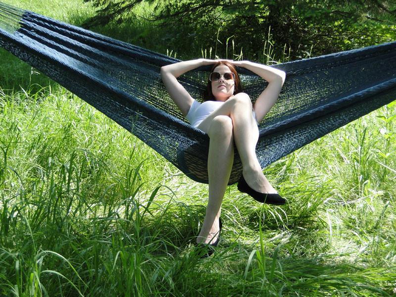 Woman relaxing in a black Mayan hammock XL with thick cord outdoors on green grass