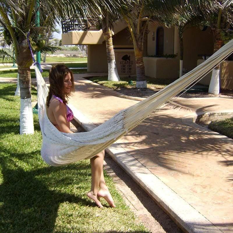 Woman relaxing in a Mayan XL natural hammock outdoors among palm trees and a garden path