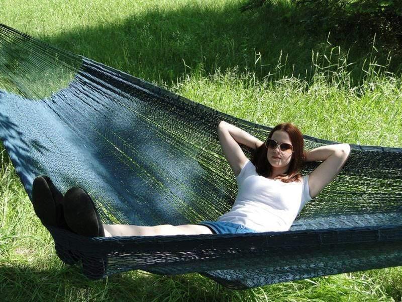 Woman relaxing on blue Mayan hammock XL thick cord outdoors in grassy field