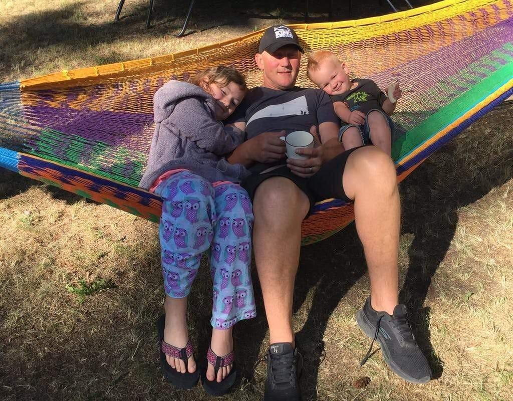 Family relaxing on colorful Mayan hammock outdoors in sunlight