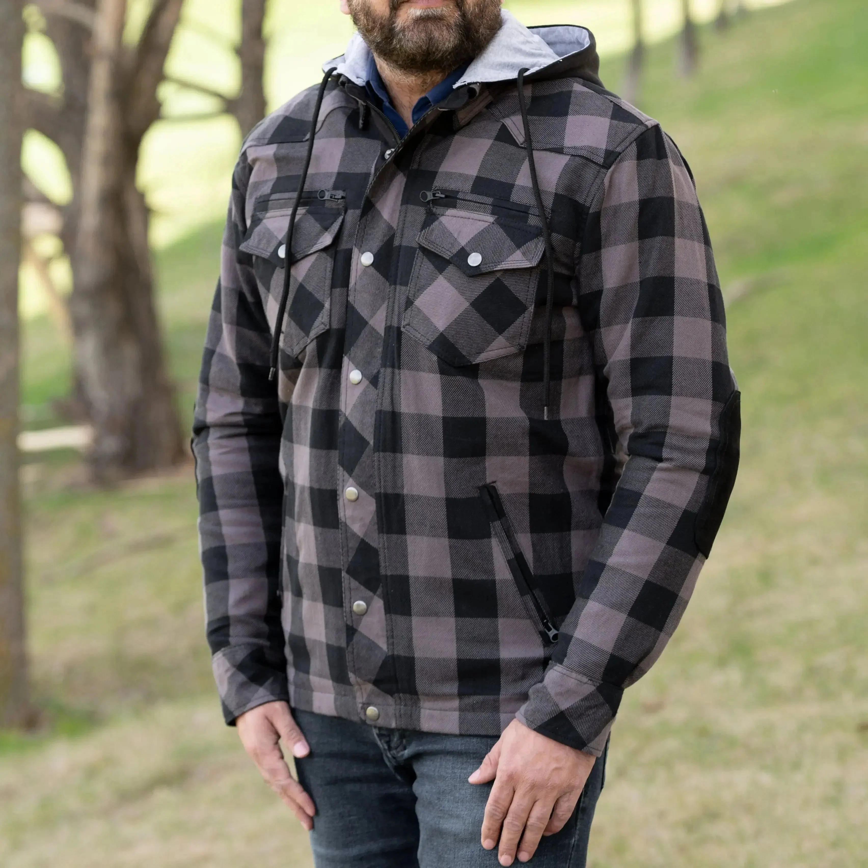 Man wearing black and grey plaid hooded jacket outdoors on grass background