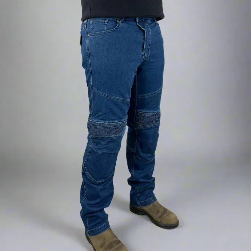 Man wearing blue reinforced motorcycle jeans and brown boots on a plain background