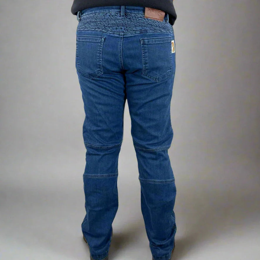 Back view of person wearing blue elastic waist denim jeans and black top on gray background