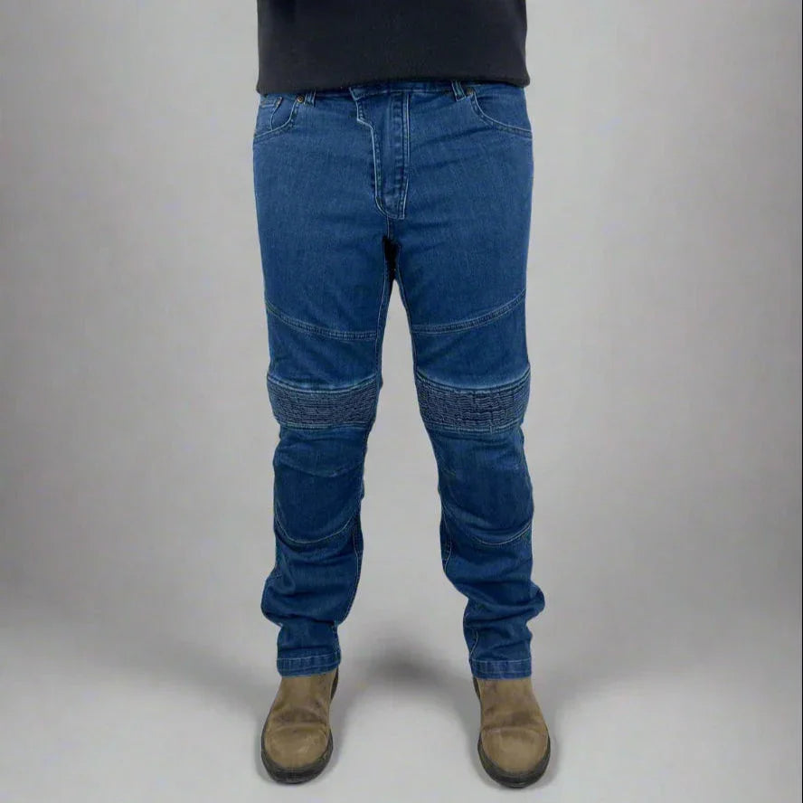 Man wearing blue moto jeans with ribbed knee panels and tan work boots in studio