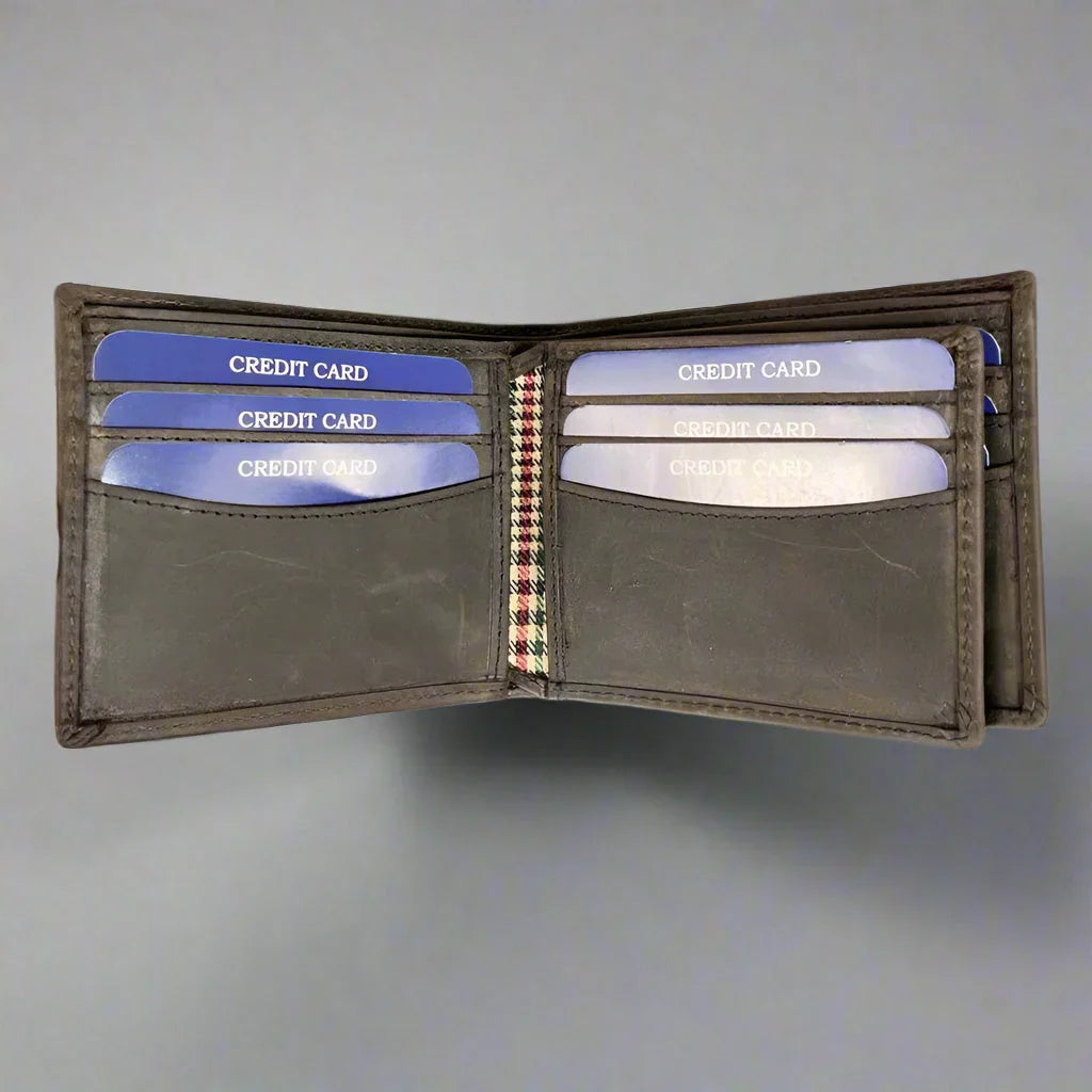 Open brown leather wallet with multiple blue credit cards on a gray background